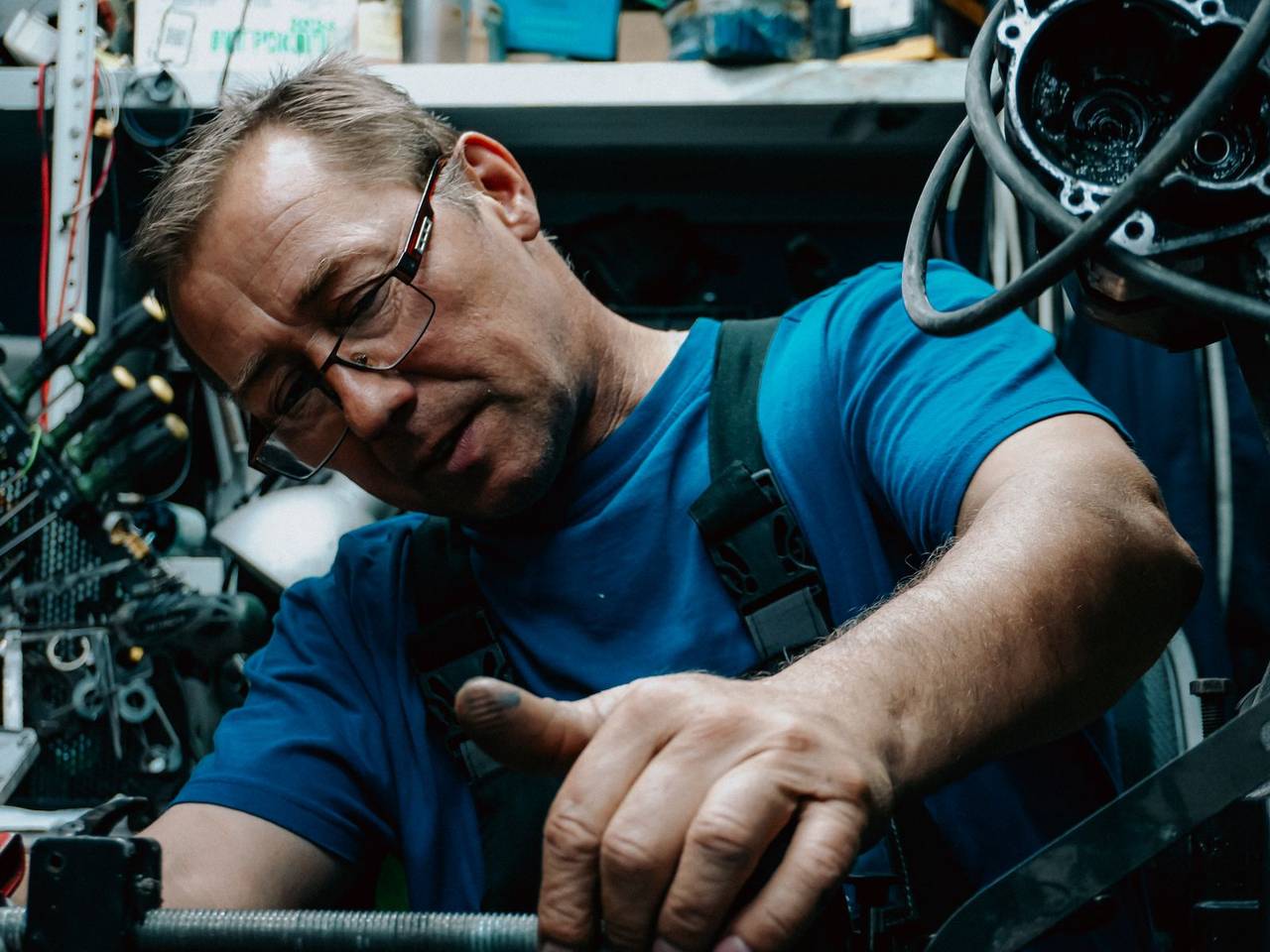 A mechanic in work gloves repairing a car in the shop