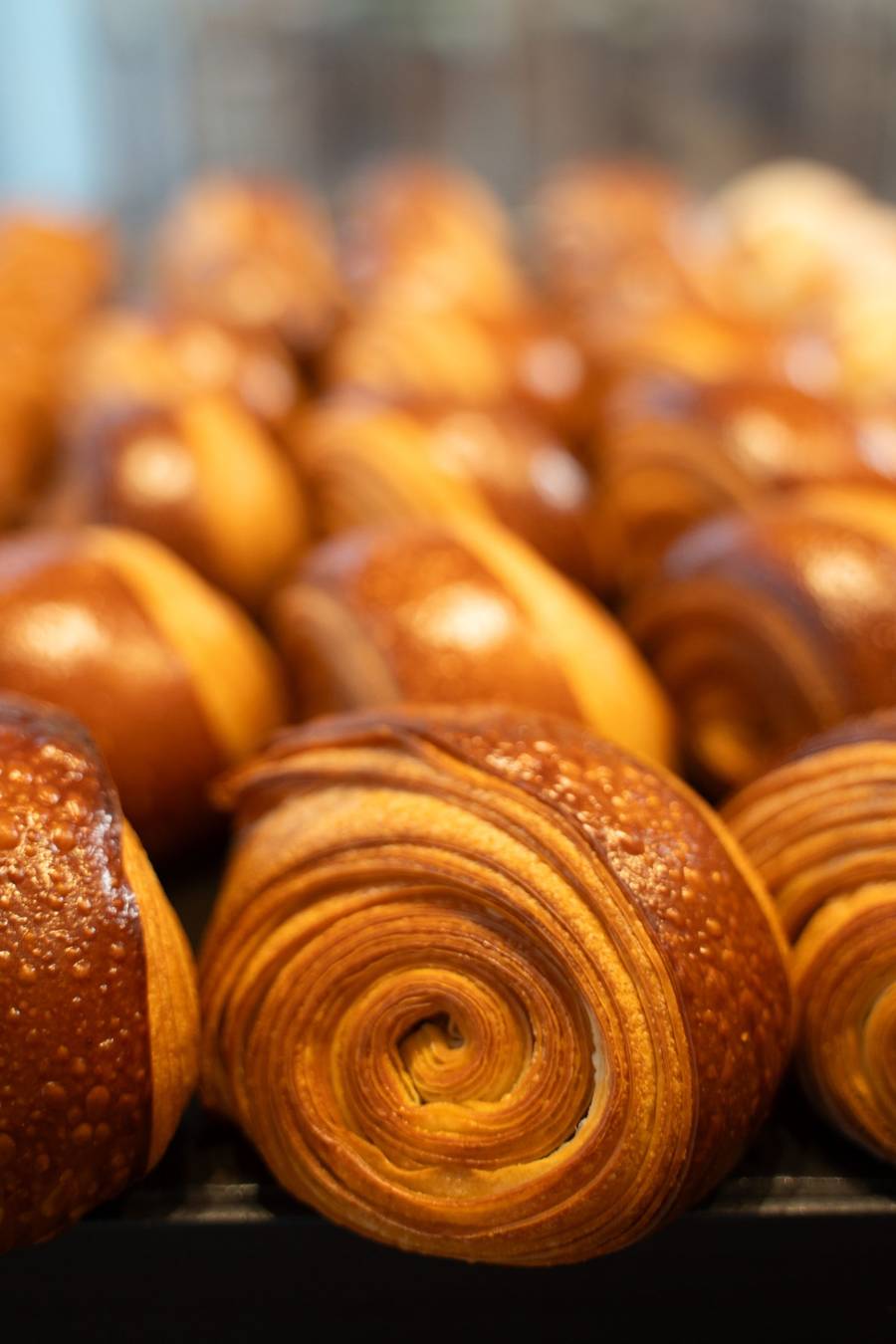 Golden laminated croissants stacked on a tray