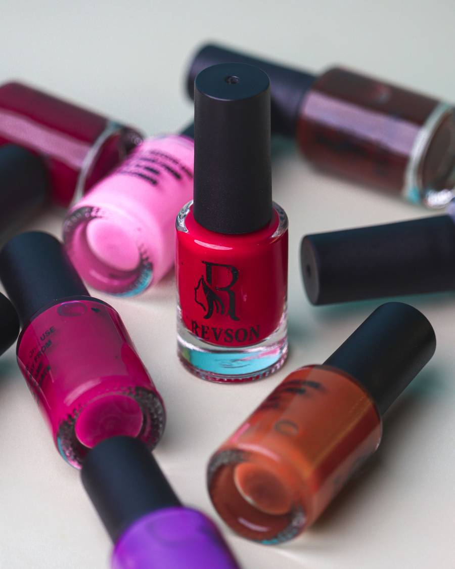 A row of nail polish bottles in pinks and reds