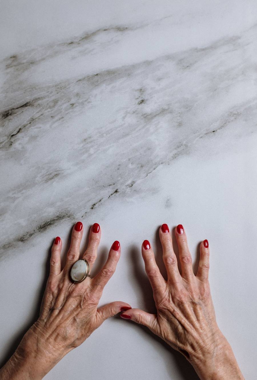 Manicured hands resting on white marble